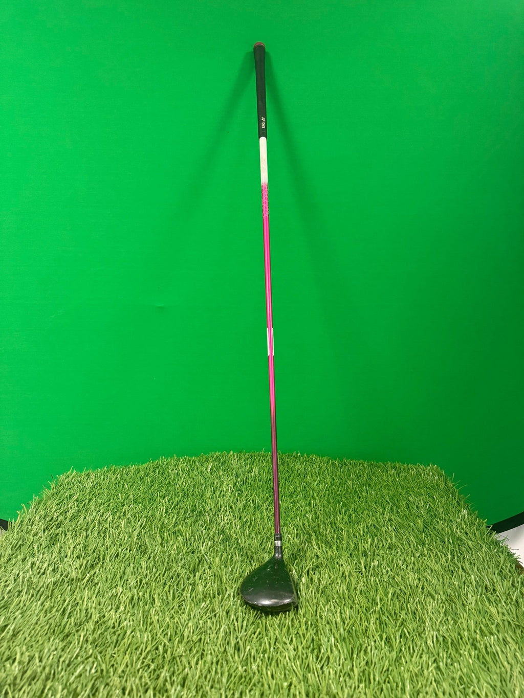 Yonex Ladies 5 wood golf club with pink and white shaft standing upright on artificial grass