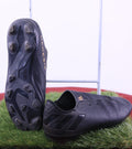 Bottom view and side view of black adidas Nemesis football boots on artificial grass
